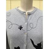 You are pert and pretty in a charming vintage-inspired cardigan. Smooth 100% cotton intarsia embellishes this soft knit, featuring two playful cats reaching for an embroidered butterfly. Accentuated by a detachable FAKE fur trim collar, appliqued elbow patches and delicate pearl buttons, this retro look inspires.  Heather grey with black pattern and collar.  100% cotton Detachable fur collar buttons on/off Appliquéd elbow patches Hand wash or machine wash gentle cycle Front button closure
